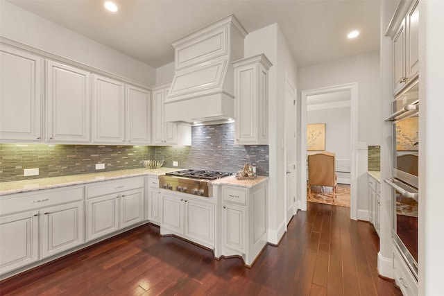 kitchen featuring white cabinetry, light stone counters, appliances with stainless steel finishes, dark hardwood / wood-style floors, and backsplash