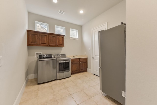 clothes washing area featuring cabinets, washing machine and dryer, sink, and light tile patterned floors