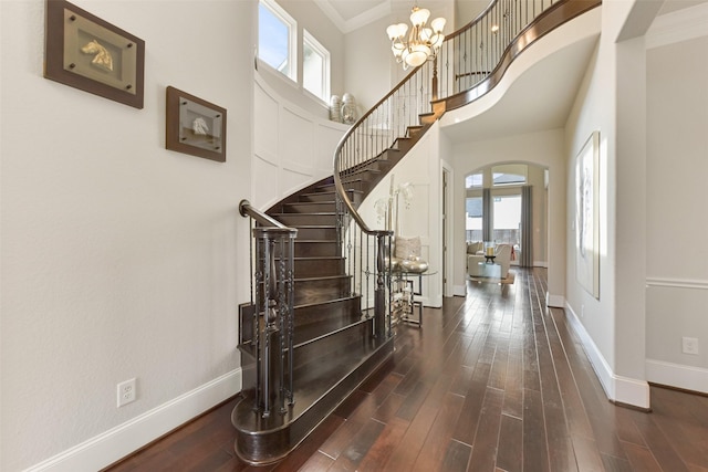 foyer entrance featuring a high ceiling, ornamental molding, dark hardwood / wood-style floors, and a chandelier