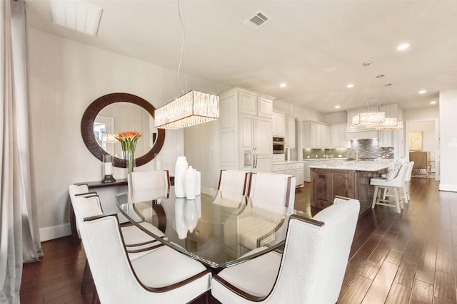 dining area featuring sink, dark wood-type flooring, and a chandelier