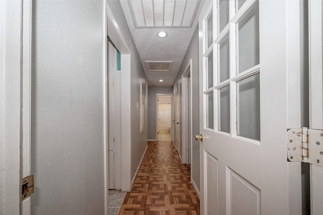 hall with dark parquet flooring and a textured ceiling