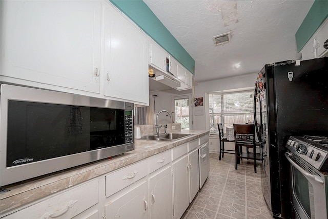 kitchen with stainless steel appliances, sink, a textured ceiling, and white cabinets