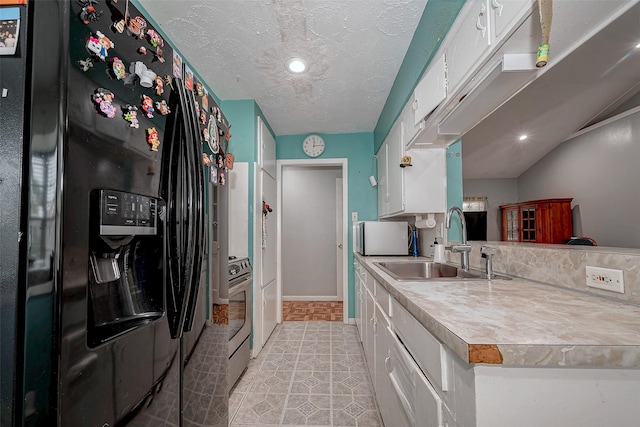 kitchen with stainless steel electric stove, white cabinetry, sink, black fridge, and a textured ceiling