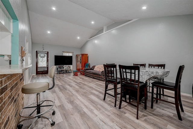 dining area with lofted ceiling and light wood-type flooring