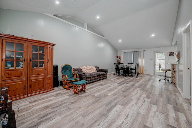 living area with high vaulted ceiling and light hardwood / wood-style flooring