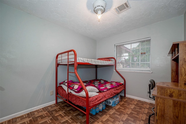 bedroom featuring a textured ceiling and dark parquet floors