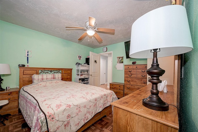 bedroom with ceiling fan, a textured ceiling, and dark parquet floors