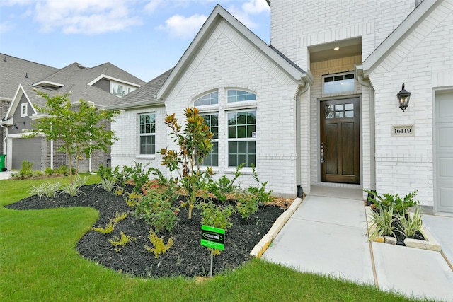 16119 Rustling Woods Rd, Conroe, TX 77302 - view of exterior entry with brick siding and a yard