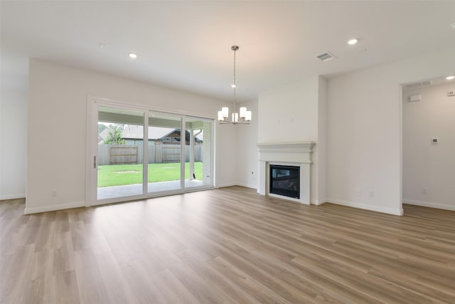 16119 Rustling Woods Rd, Conroe, TX 77302 - unfurnished living room with a chandelier, light wood-style floors, recessed lighting, and a glass covered fireplace