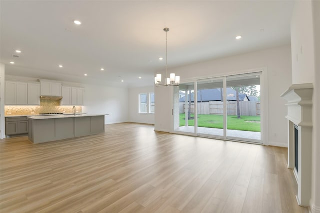 16119 Rustling Woods Rd, Conroe, TX 77302 - unfurnished living room featuring a chandelier, light wood-style flooring, recessed lighting, and a fireplace