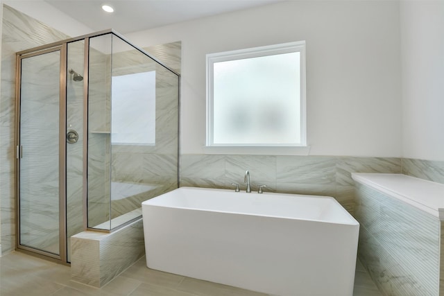 16119 Rustling Woods Rd, Conroe, TX 77302 - bathroom with a freestanding tub, a stall shower, tile patterned flooring, and tile walls