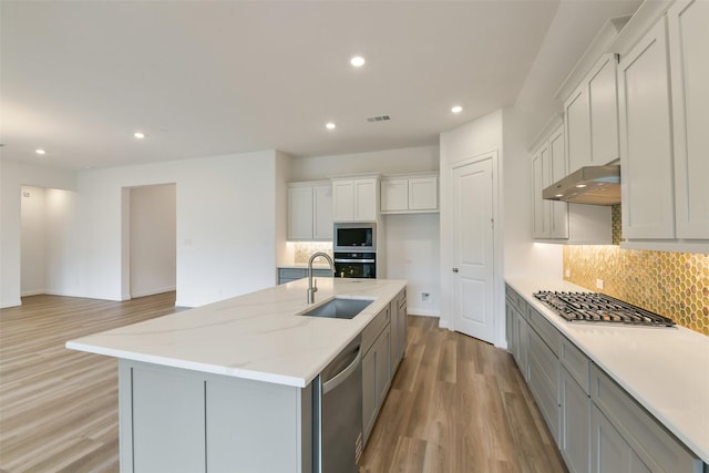 16119 Rustling Woods Rd, Conroe, TX 77302 - kitchen featuring stainless steel appliances, extractor fan, light wood finished floors, backsplash, and recessed lighting