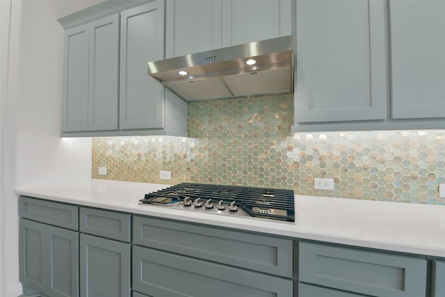 16119 Rustling Woods Rd, Conroe, TX 77302 - kitchen with under cabinet range hood, stainless steel gas cooktop, light countertops, and tasteful backsplash