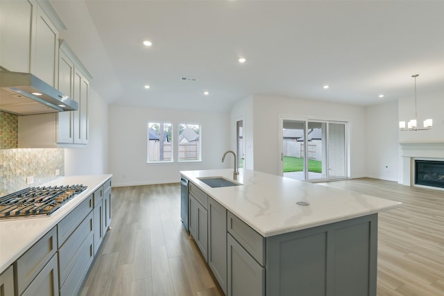 16119 Rustling Woods Rd, Conroe, TX 77302 - kitchen with gray cabinets, appliances with stainless steel finishes, light wood-style floors, decorative backsplash, and open floor plan