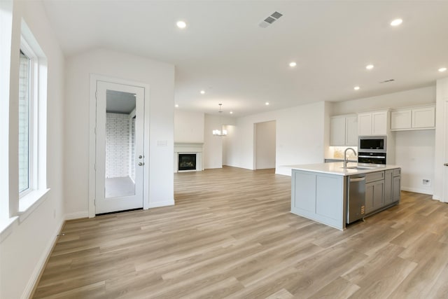 16119 Rustling Woods Rd, Conroe, TX 77302 - kitchen featuring appliances with stainless steel finishes, light wood finished floors, recessed lighting, light countertops, and open floor plan
