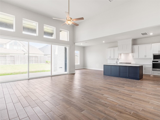 10903 Providence Ct, Missouri City, TX 77459 - unfurnished living room with a ceiling fan, light wood-style floors, a high ceiling, and recessed lighting