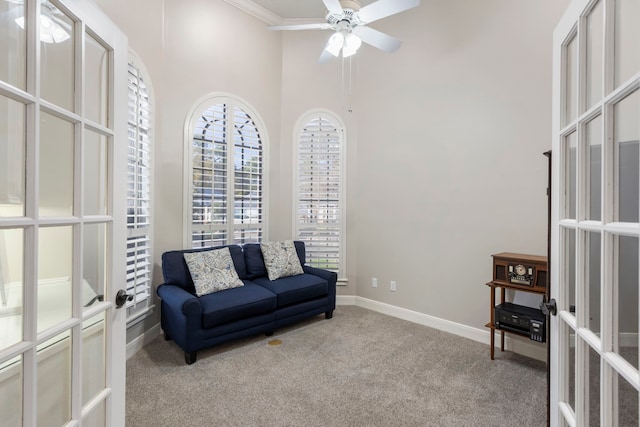 living area with french doors, ceiling fan, light carpet, and a towering ceiling