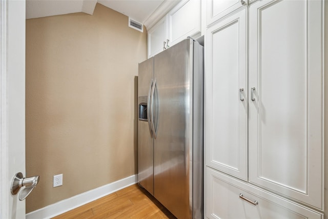 kitchen with light wood-type flooring, stainless steel fridge with ice dispenser, and white cabinets