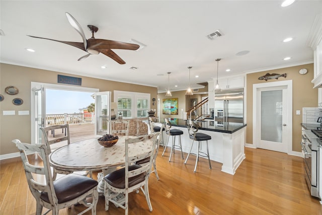 dining space with crown molding and light wood-type flooring