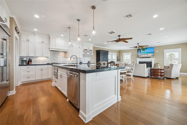 kitchen featuring pendant lighting, sink, light hardwood / wood-style flooring, an island with sink, and white cabinets