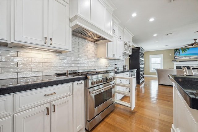 kitchen with white cabinetry, tasteful backsplash, high end stove, and custom range hood