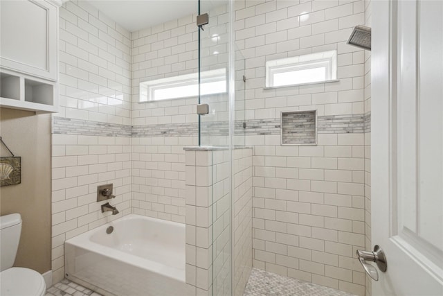bathroom featuring enclosed tub / shower combo, plenty of natural light, and toilet