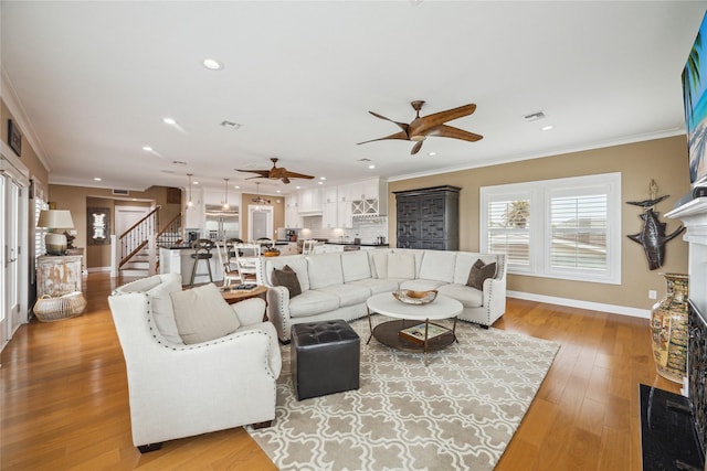 living room with light hardwood / wood-style flooring, ornamental molding, and ceiling fan