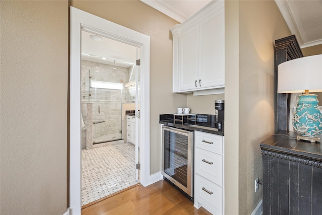 kitchen with wine cooler, hardwood / wood-style flooring, ornamental molding, and white cabinets