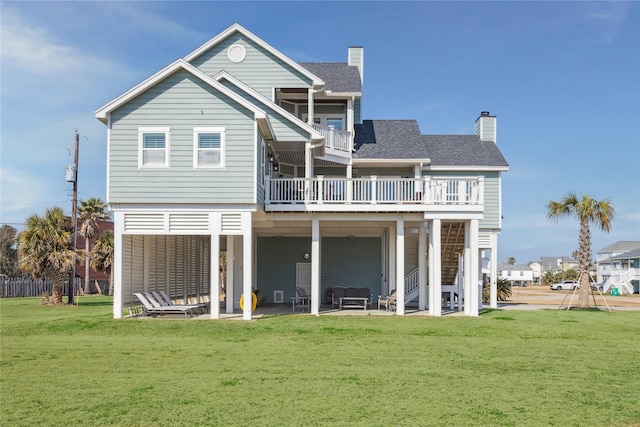 rear view of property with a lawn, a balcony, and a patio area