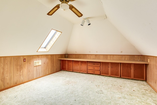 bonus room featuring ceiling fan, lofted ceiling, light carpet, and wood walls