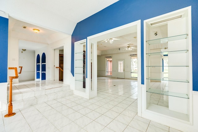 tiled empty room with vaulted ceiling and ceiling fan