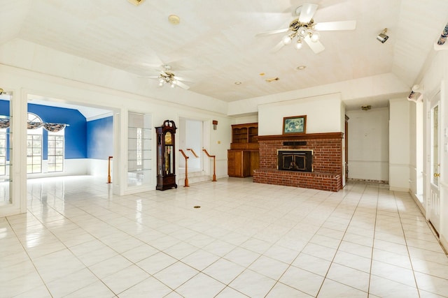 unfurnished living room with a brick fireplace, a raised ceiling, ceiling fan, and light tile patterned flooring