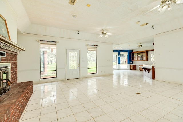 unfurnished living room featuring plenty of natural light, a raised ceiling, ceiling fan, and light tile patterned flooring