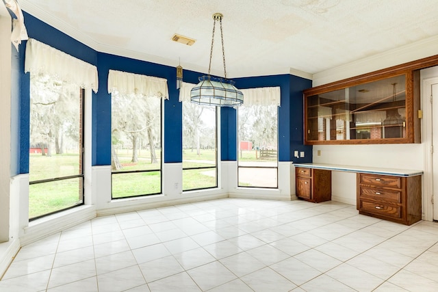 unfurnished dining area with crown molding, built in desk, a textured ceiling, and light tile patterned flooring