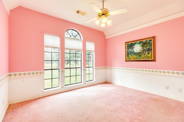 empty room featuring a wealth of natural light, vaulted ceiling, ceiling fan, and carpet flooring