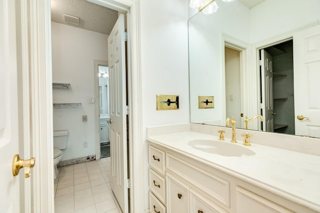 bathroom with tile patterned floors, toilet, vanity, and a textured ceiling