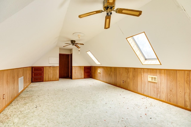 bonus room with ceiling fan, lofted ceiling, light colored carpet, and wooden walls