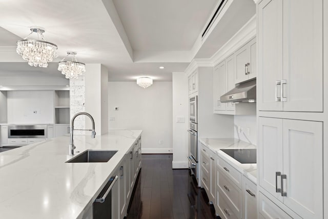 kitchen featuring appliances with stainless steel finishes, white cabinets, light stone countertops, and decorative light fixtures