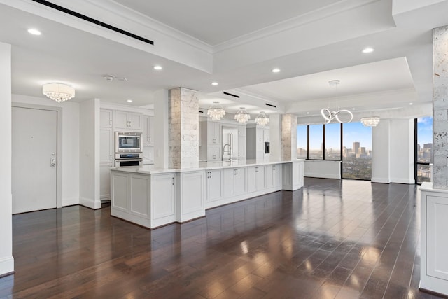 kitchen featuring a tray ceiling, appliances with stainless steel finishes, white cabinets, a chandelier, and pendant lighting