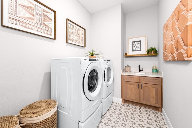 clothes washing area featuring cabinets, sink, and washer and dryer