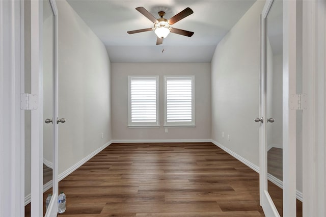 empty room featuring dark wood-type flooring, vaulted ceiling, and ceiling fan