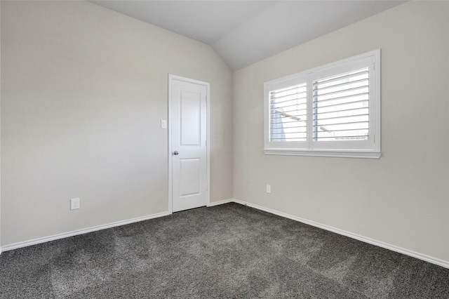 empty room with lofted ceiling and dark carpet