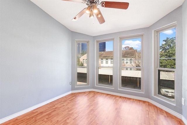 spare room featuring ceiling fan, vaulted ceiling, wood finished floors, and baseboards