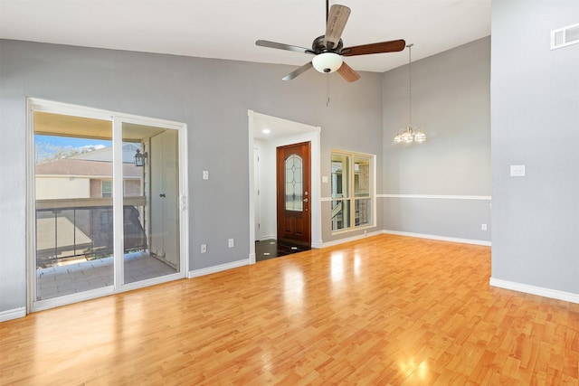 interior space featuring baseboards, ceiling fan with notable chandelier, visible vents, and light wood-style floors