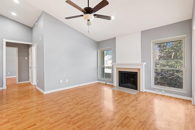 unfurnished living room with a fireplace with flush hearth, vaulted ceiling, light wood-style floors, and baseboards