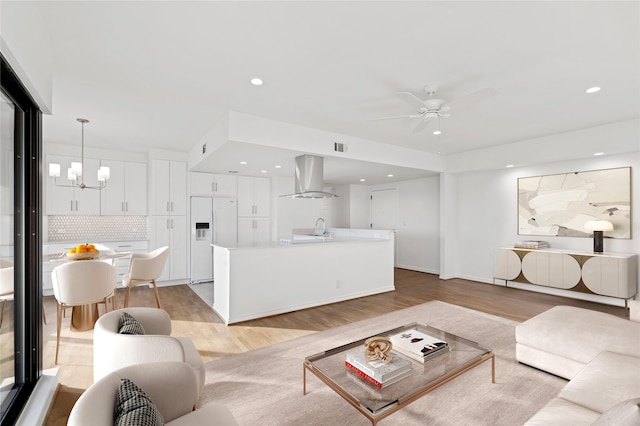 living area featuring recessed lighting, visible vents, light wood-style flooring, and ceiling fan with notable chandelier