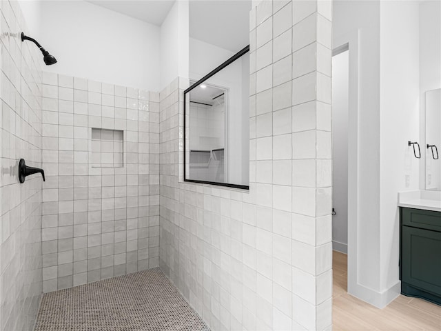 bathroom with vanity, hardwood / wood-style flooring, and tiled shower