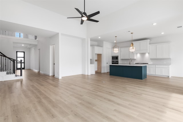 10914 Prospect Hill Ct, Missouri City, TX 77459 - unfurnished living room featuring a ceiling fan, light wood-style floors, stairs, recessed lighting, and a high ceiling