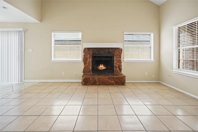 unfurnished living room with plenty of natural light, light tile patterned floors, lofted ceiling, and a fireplace