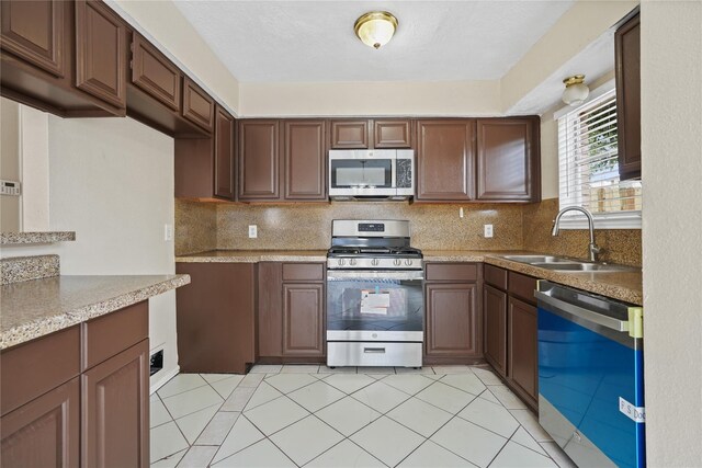 kitchen featuring stainless steel appliances, sink, decorative backsplash, and light tile patterned floors